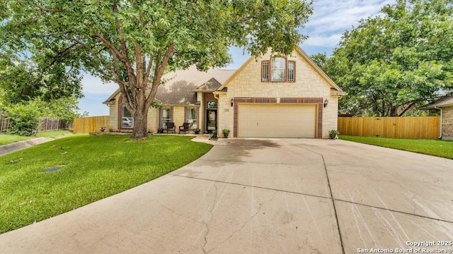 view of front of home with stone siding, driveway, fence, and a front yard