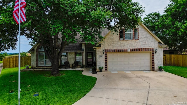 traditional-style house with stone siding, fence, a front lawn, and concrete driveway