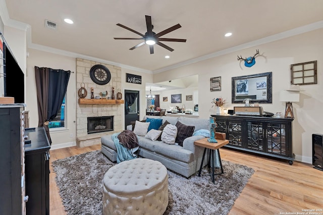 living area with light wood finished floors, a fireplace, ceiling fan, and ornamental molding