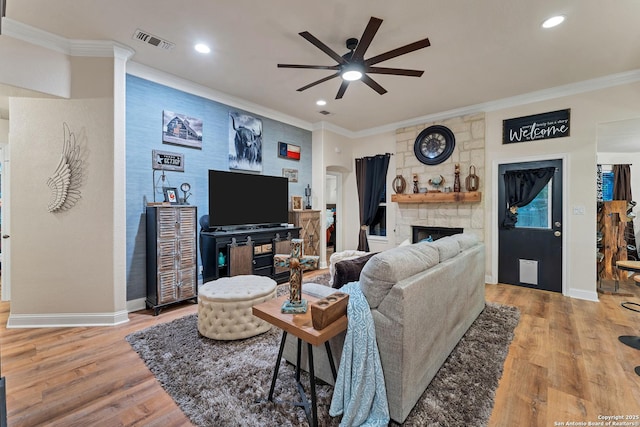 living area with a ceiling fan, wood finished floors, baseboards, visible vents, and ornamental molding