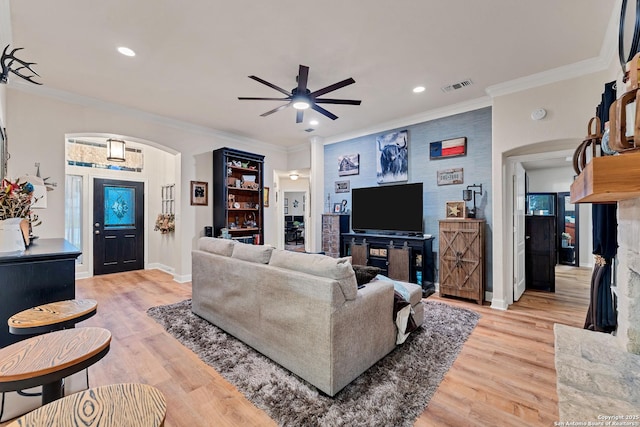 living area with light wood-style flooring, visible vents, arched walkways, and a ceiling fan