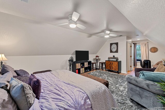 bedroom featuring lofted ceiling, a textured ceiling, visible vents, a ceiling fan, and wood finished floors