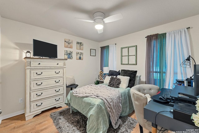 bedroom with a ceiling fan, baseboards, and light wood-style floors