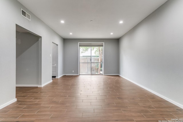 unfurnished room featuring baseboards, visible vents, and wood finished floors