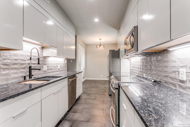kitchen with dark stone countertops, white cabinets, a sink, and appliances with stainless steel finishes