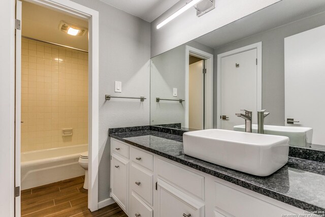 bathroom with toilet, vanity, shower / bathtub combination, and wood tiled floor