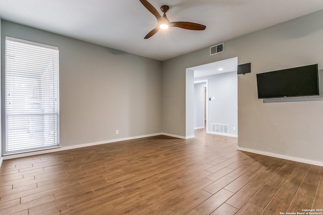 spare room featuring wood finished floors, baseboards, ceiling fan, and visible vents
