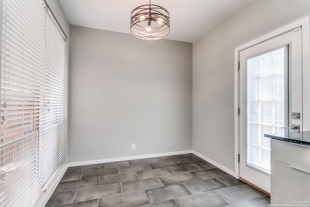 unfurnished dining area featuring a notable chandelier and baseboards