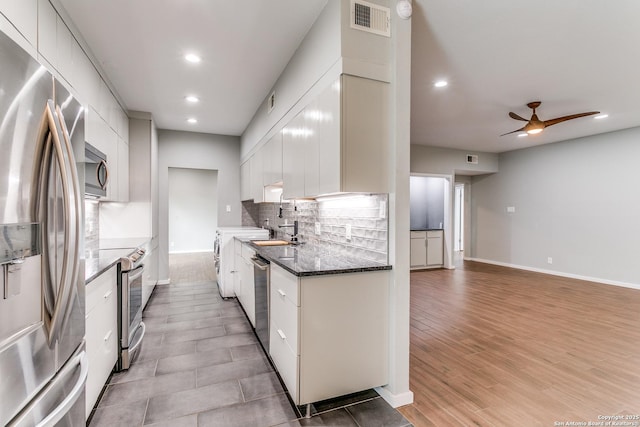 kitchen with a sink, a ceiling fan, backsplash, white cabinetry, and stainless steel appliances