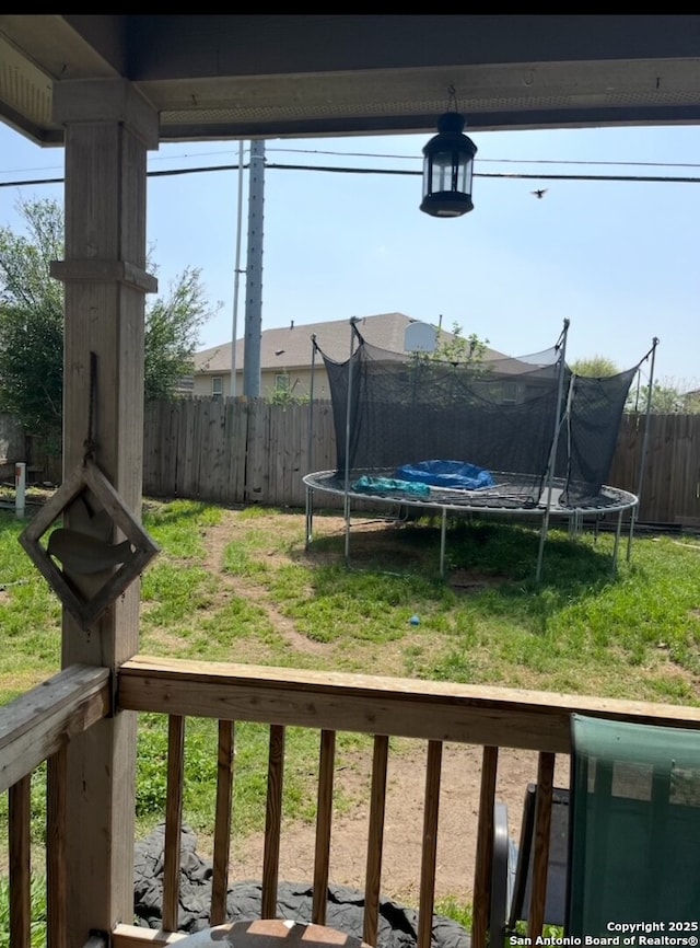 view of yard with a trampoline and fence
