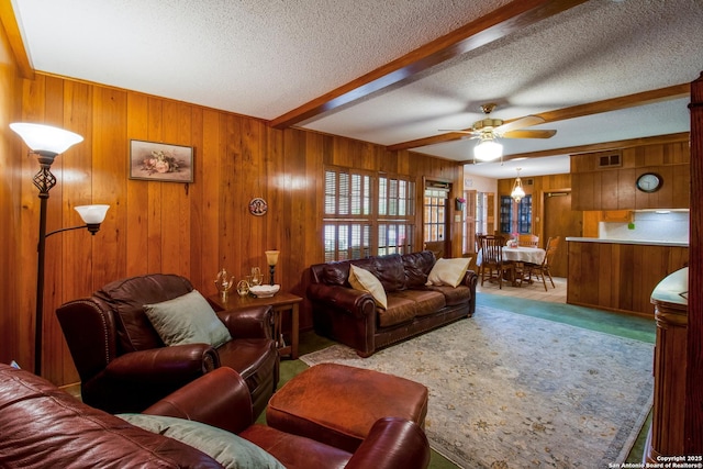 3422 William Penn Dr, San Antonio, TX 78230 - carpeted living room with a ceiling fan, beam ceiling, wood walls, and a textured ceiling