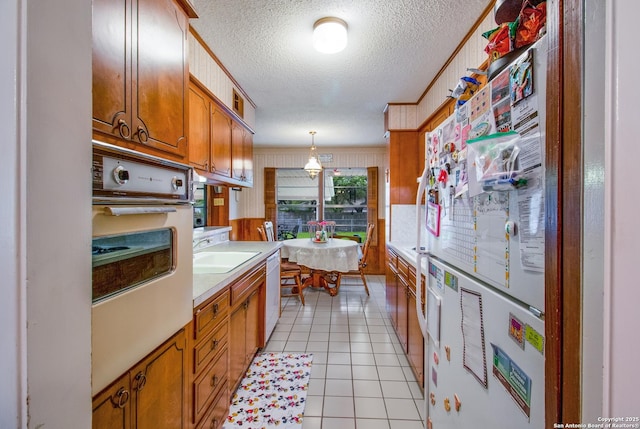 3422 William Penn Dr, San Antonio, TX 78230 - kitchen with light countertops, dishwasher, oven, brown cabinetry, and light tile patterned floors