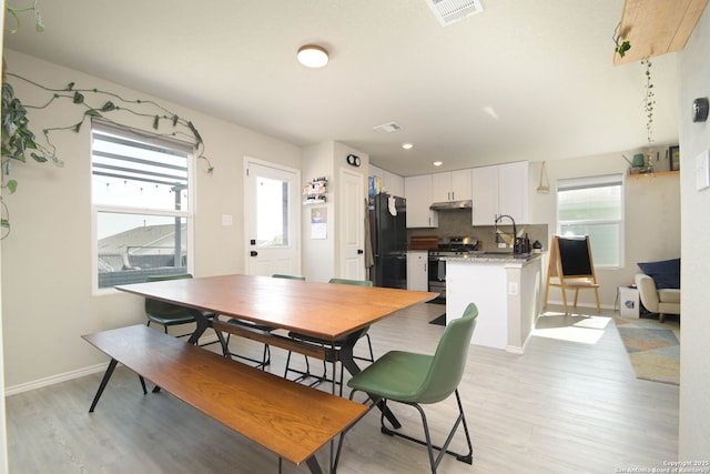 dining area with visible vents, light wood-style floors, and a healthy amount of sunlight