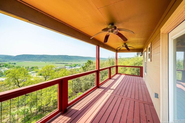 wooden terrace with a mountain view and a ceiling fan