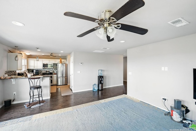kitchen featuring backsplash, a kitchen breakfast bar, appliances with stainless steel finishes, a peninsula, and visible vents