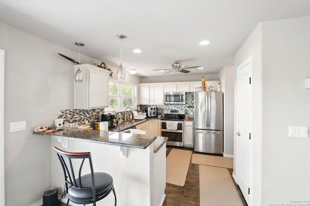 kitchen with a ceiling fan, tasteful backsplash, a kitchen breakfast bar, appliances with stainless steel finishes, and a peninsula