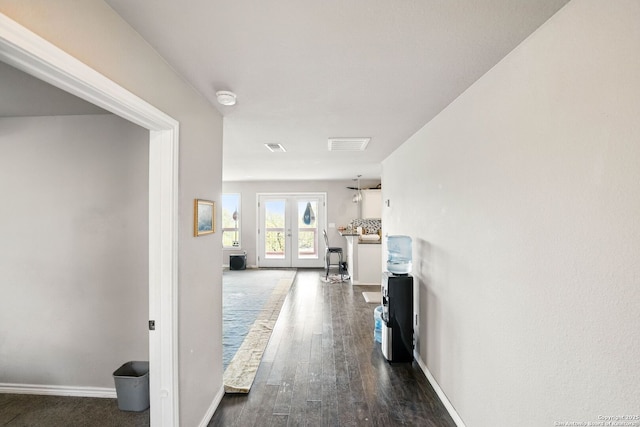 hall featuring dark wood-type flooring, baseboards, visible vents, and french doors