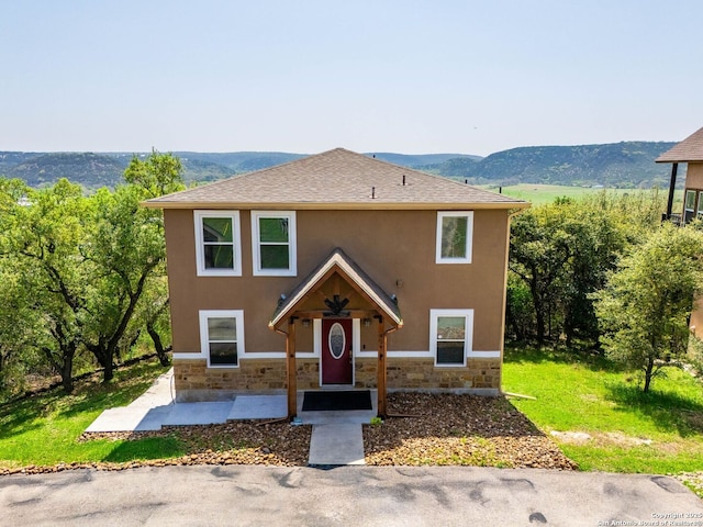 view of front of home with stone siding, a mountain view, stucco siding, and a patio area