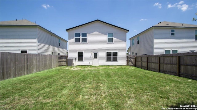 rear view of house with a yard and a fenced backyard