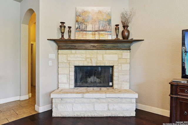 interior details with baseboards, arched walkways, and wood finished floors