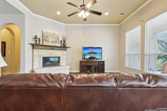 living room featuring visible vents, a ceiling fan, ornamental molding, and arched walkways
