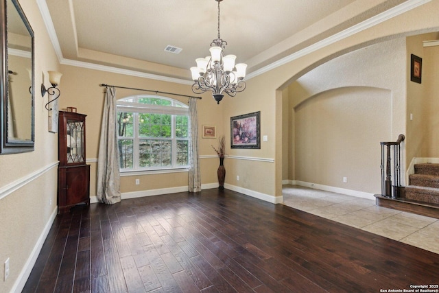 empty room with arched walkways, an inviting chandelier, stairs, and hardwood / wood-style floors