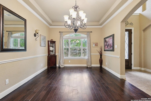 unfurnished room with hardwood / wood-style flooring, a chandelier, a tray ceiling, baseboards, and arched walkways