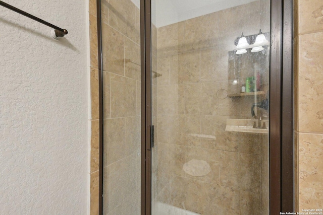 bathroom with a textured wall and a shower stall