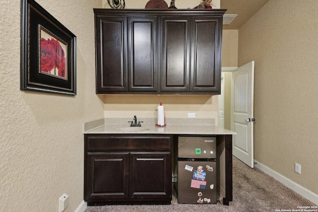 interior space featuring a textured wall, light countertops, and baseboards