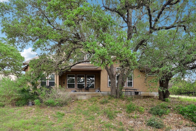back of property with stucco siding and covered porch