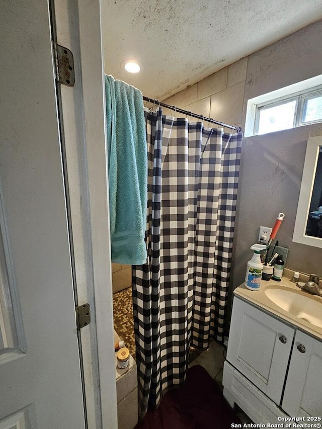 bathroom featuring curtained shower, vanity, and a textured ceiling