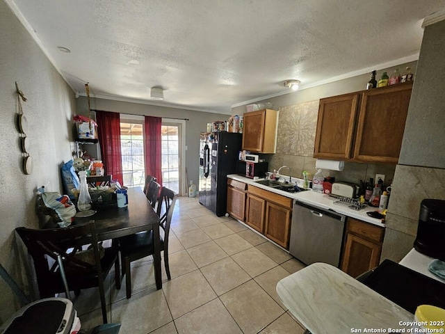 kitchen featuring light countertops, a sink, black refrigerator with ice dispenser, stainless steel dishwasher, and light tile patterned floors