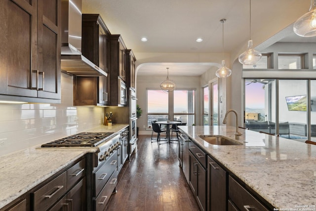 6743 Bella Colina, San Antonio, TX 78256 - kitchen featuring light stone countertops, wall chimney exhaust hood, dark wood finished floors, a sink, and backsplash