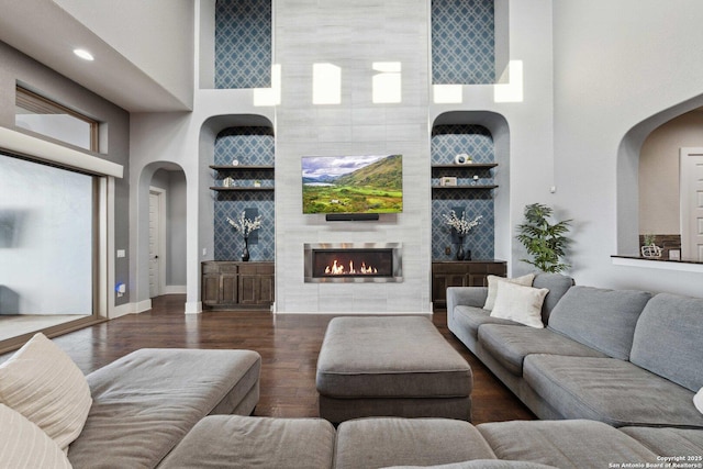6743 Bella Colina, San Antonio, TX 78256 - living room featuring baseboards, a high ceiling, arched walkways, a fireplace, and wood finished floors