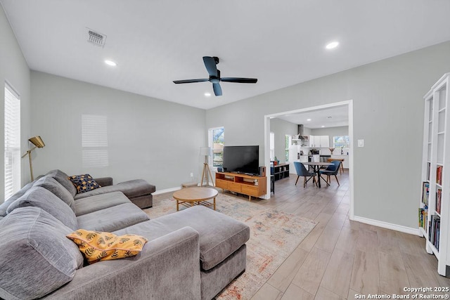 living room featuring baseboards, a wealth of natural light, visible vents, and light wood-type flooring