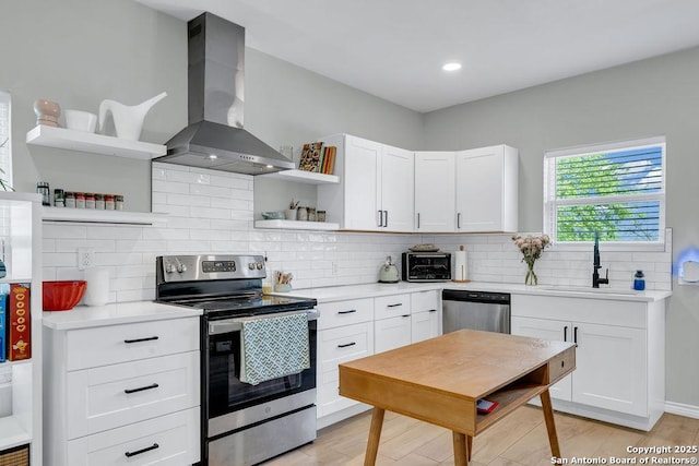 kitchen featuring light countertops, open shelves, wall chimney exhaust hood, stainless steel appliances, and white cabinets