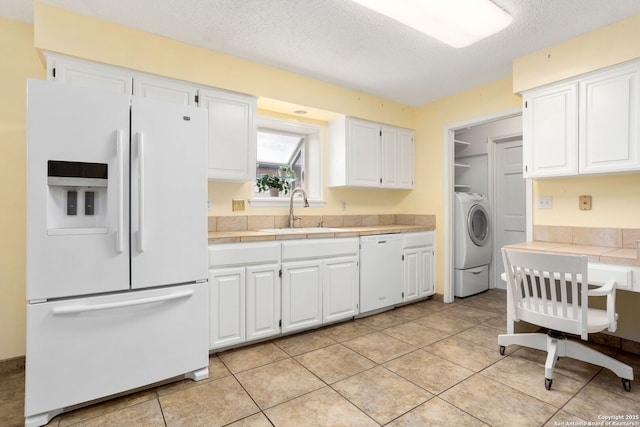 kitchen featuring tile counters, white appliances, a sink, washer / dryer, and white cabinets