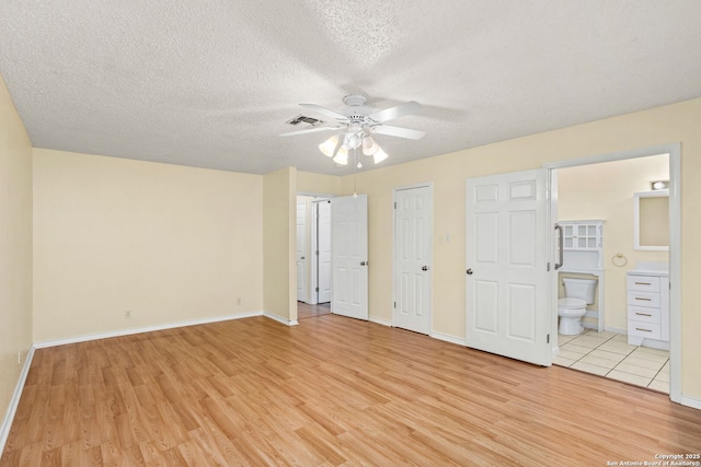 unfurnished bedroom featuring baseboards, visible vents, light wood-style floors, and a textured ceiling