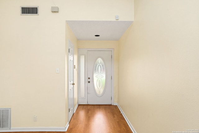 doorway featuring wood finished floors, baseboards, and visible vents
