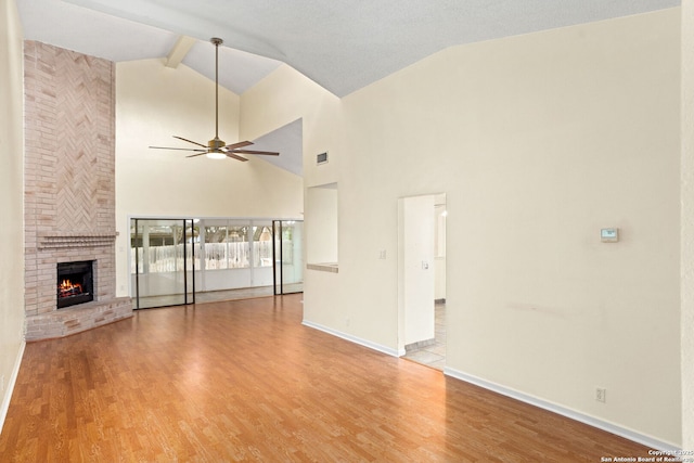 unfurnished living room with a ceiling fan, vaulted ceiling with beams, a brick fireplace, light wood-type flooring, and baseboards