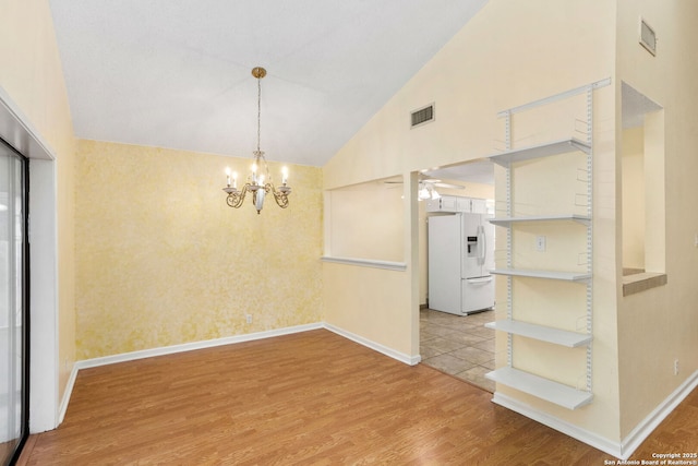 unfurnished room with high vaulted ceiling, baseboards, ceiling fan with notable chandelier, visible vents, and light wood-style floors