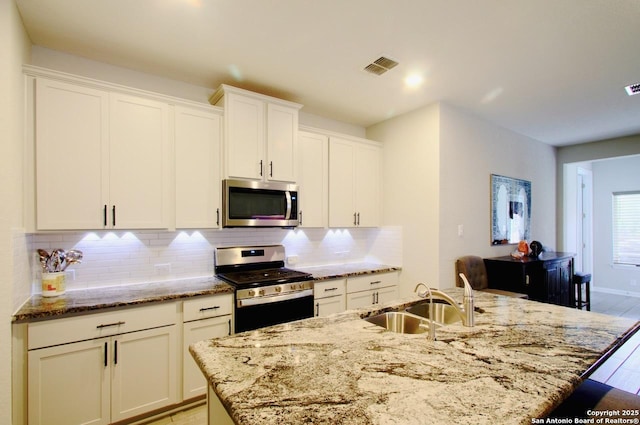 kitchen with a sink, tasteful backsplash, appliances with stainless steel finishes, visible vents, and white cabinets