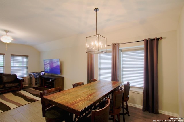 dining area featuring baseboards, wood finished floors, vaulted ceiling, and a notable chandelier