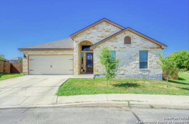 view of front of home featuring stone siding, concrete driveway, fence, a garage, and a front yard