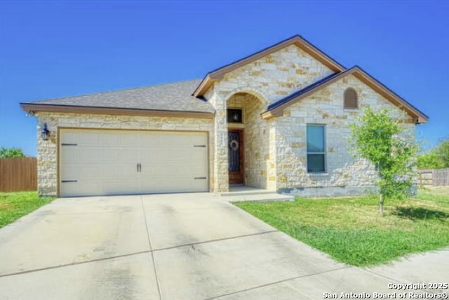 french country home with stone siding, concrete driveway, fence, and a garage