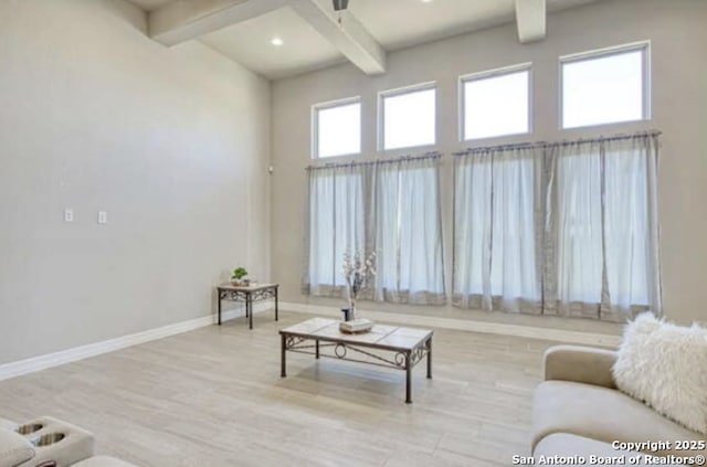 living room featuring baseboards, a towering ceiling, wood finished floors, and beam ceiling