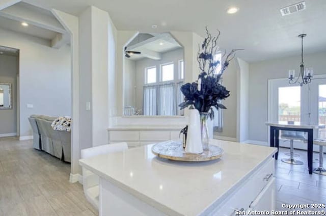 interior space with white cabinets, light countertops, visible vents, and an inviting chandelier