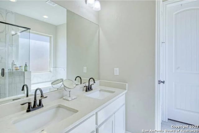 bathroom featuring a sink, double vanity, and a stall shower