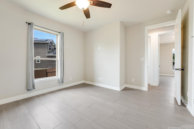spare room featuring ceiling fan, baseboards, and plenty of natural light