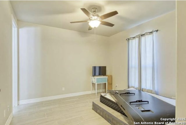interior space featuring ceiling fan, baseboards, and a healthy amount of sunlight